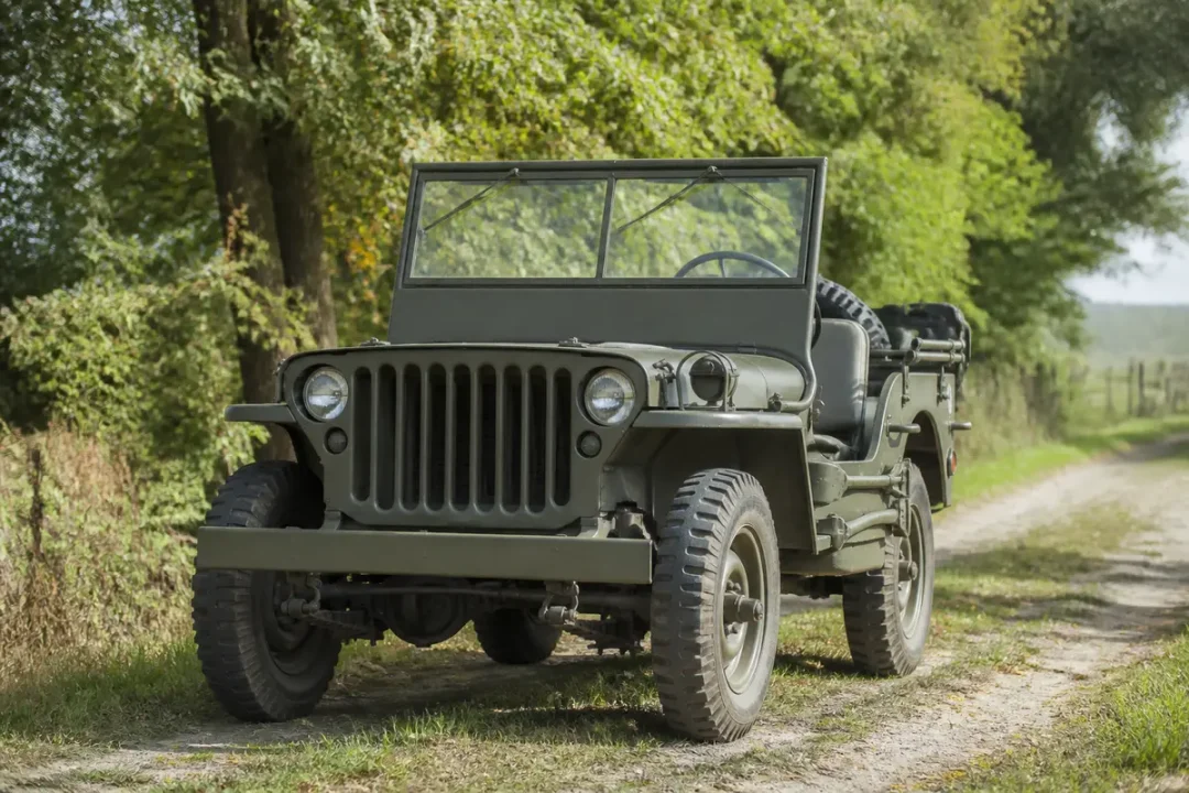 Ancienne jeep militaire sur chemin forestier, entourée de verdure et arbres majestueux