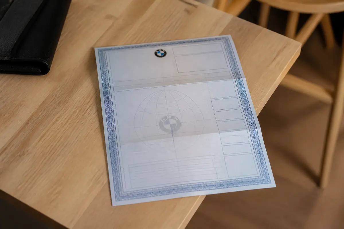 Document officiel BMW sur une table incluant un certificat de conformité pour BMW