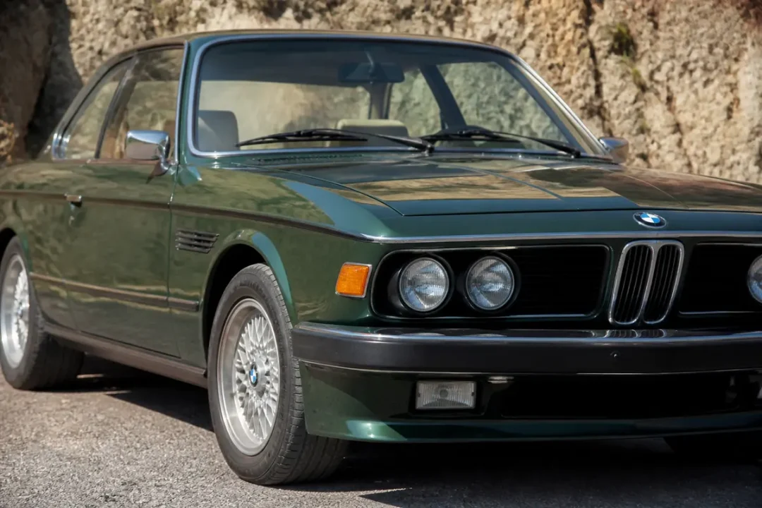 Voiture classique verte, phare rond, modèle cs 3.0 BMW stationnée sur une route.
