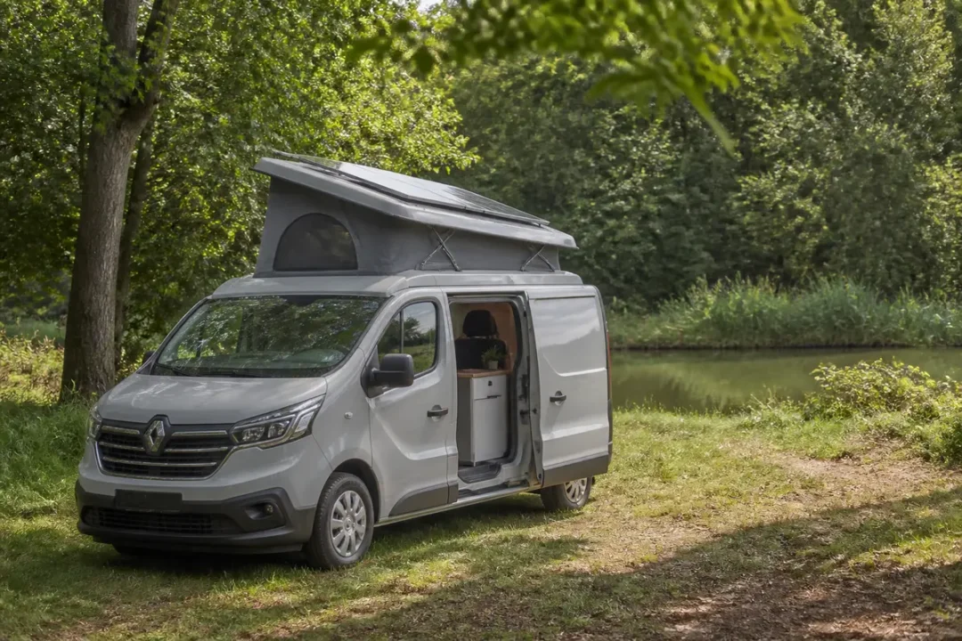 Van aménagé avec toit relevable, stationné près d'un lac, idéal pour trafic aménagé