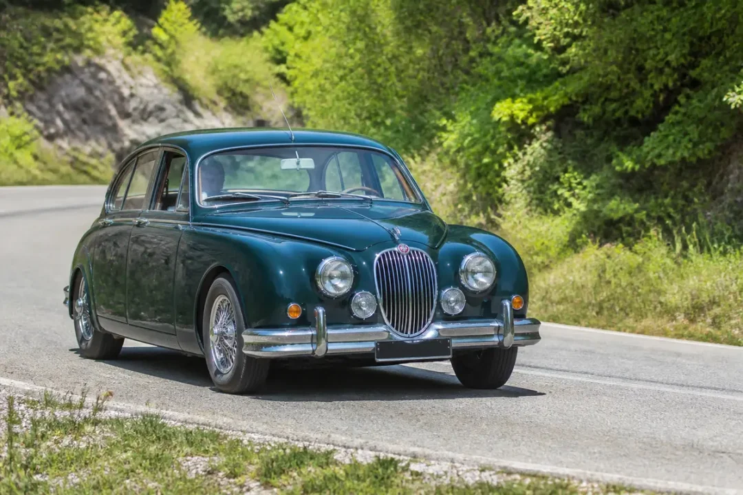 Voiture classique verte en pleine campagne, modèle Jaguar Mk2 auto vintage.
